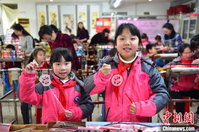 圖為小學生展示繡制好的2022年北京冬奧會吉祥物“冰墩墩”形象?！∮髟屏?攝