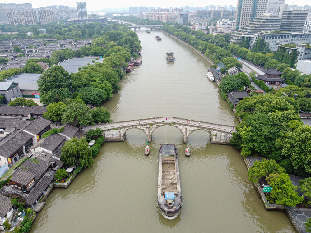 5月27日，一艘貨船駛過(guò)京杭大運(yùn)河南端標(biāo)志建筑杭州拱宸橋。(無(wú)人機(jī)照片)新華社記者江漢 攝