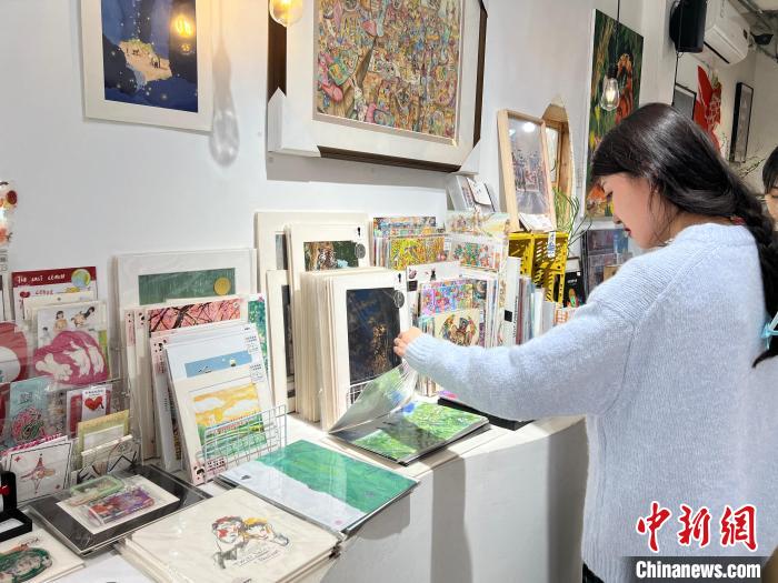 圖為藝術(shù)品商店內(nèi)，顧客挑選插畫作品?！＄婌?攝