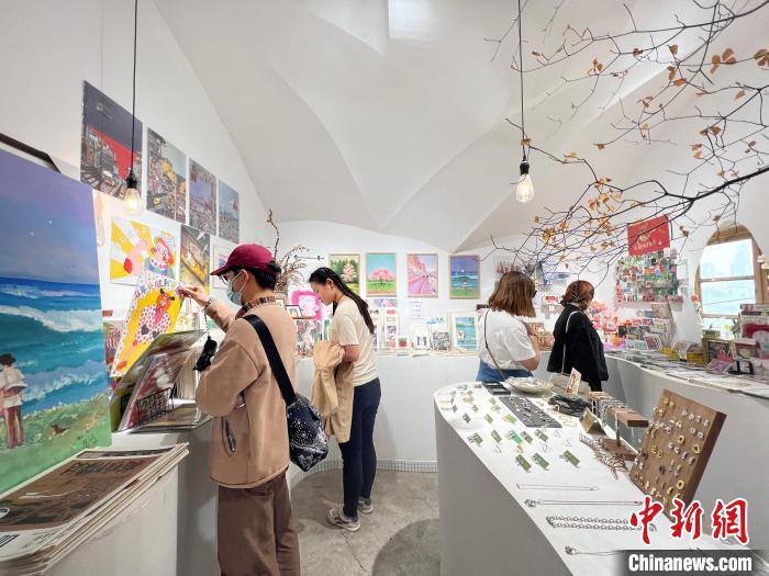 圖為藝術(shù)品商店內(nèi)，顧客挑選插畫作品?！＄婌?攝