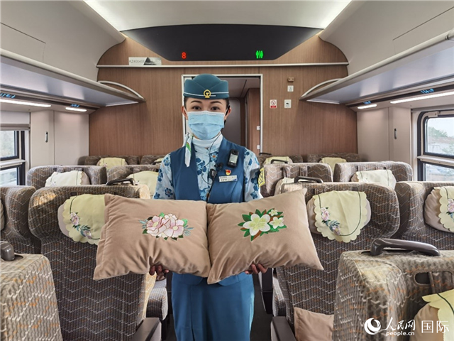 趙瑩靜展示中老鐵路國際旅客列車?yán)飵в兄袊档せê屠蠐胝及突ù汤C圖案的靠墊。人民網(wǎng)記者 杜明明攝