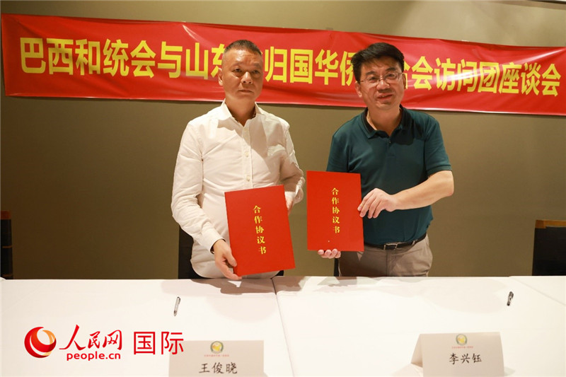 中國僑聯(lián)副主席、山東省僑聯(lián)主席李興鈺（右）與巴西和統(tǒng)會會長王俊曉簽署合作協(xié)議書。人民網(wǎng)記者 陳海琪攝