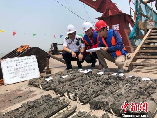圖為勘察設(shè)計人員與海事局工作人員查看巖芯情況?！∥赫?攝