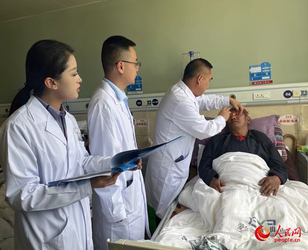 董光明（左三）帶領(lǐng)醫(yī)生對患者進行術(shù)前檢查。人民網(wǎng)記者 杜燕飛攝