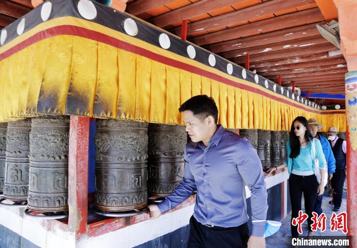 圖為外籍嘉賓體驗藏族傳統(tǒng)轉經筒?！●R銘言 攝