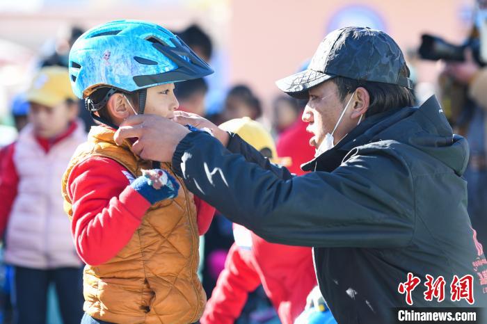 圖為拉薩市實(shí)驗(yàn)幼兒園孩子在教練的幫助下穿戴頭盔?！『闻罾?攝