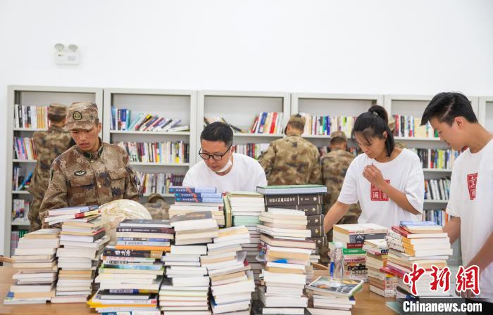 圖為志愿者們和邊防戰(zhàn)士整理圖書?！詵| 攝
