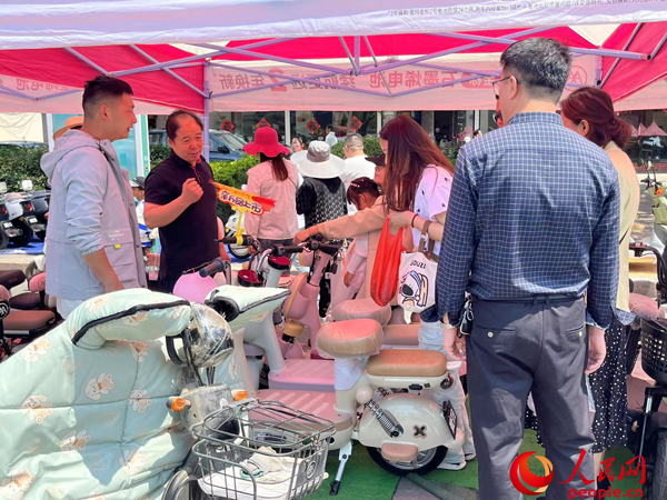某電動自行車品牌工作人員向消費(fèi)者介紹以舊換新相關(guān)情況。人民網(wǎng)記者 杜燕飛攝