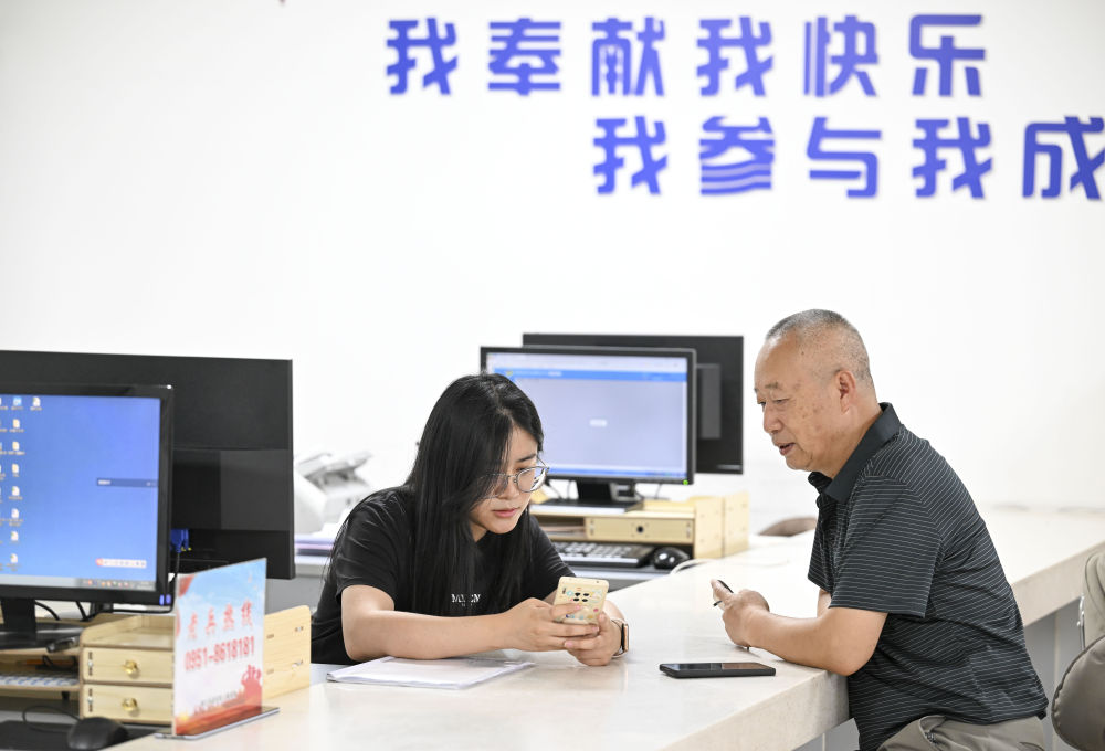 2024年6月20日，在寧夏銀川市金鳳區(qū)長城花園社區(qū)黨群服務中心，工作人員幫助居民辦理業(yè)務。圖片來源 新華社