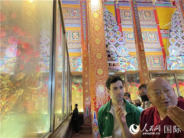 7月25日，省級非物質(zhì)文化遺產(chǎn)項目塔爾寺酥油花的代表性傳承人朋措堅參（右）在塔爾寺酥油花館講解酥油花的制作過程。人民網(wǎng) 謝瑩攝