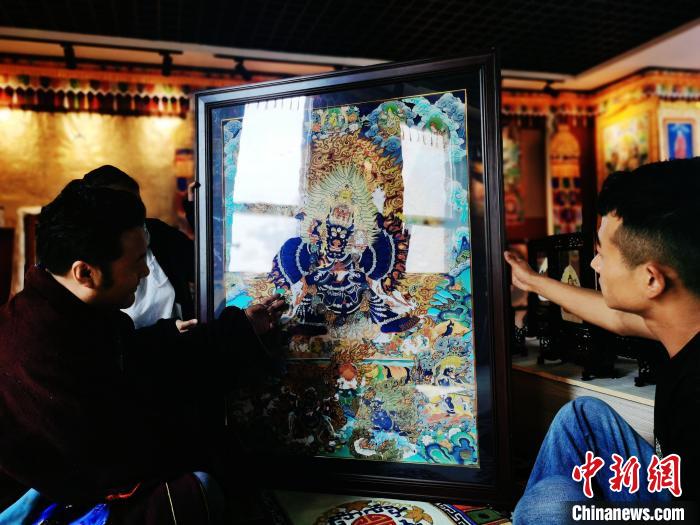 圖為久美尖措(左)與徒弟們展示唐卡作品。　張?zhí)砀?攝