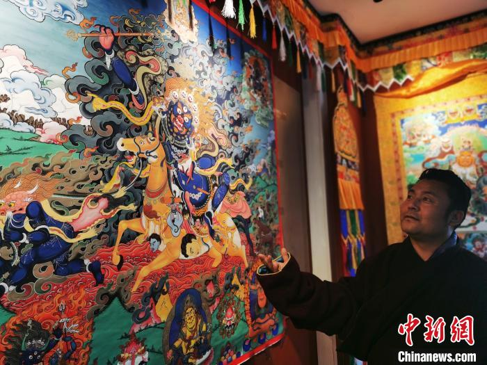 圖為久美尖措展示唐卡作品?！?zhí)砀?攝