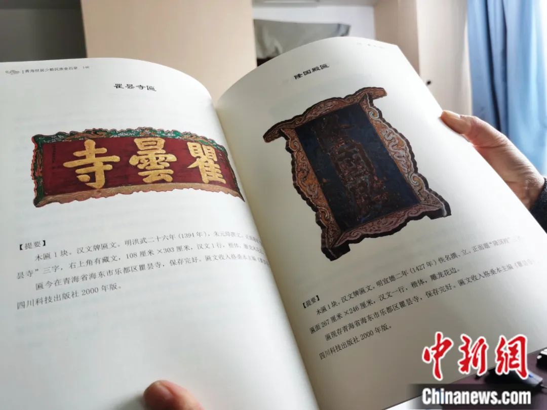 古籍保護(hù)人員展示介紹明代朱元璋撰寫(xiě)的青海瞿曇寺匾(左)的出版書(shū)籍。張?zhí)砀?攝