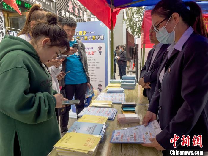 圖為工作人員正在向路過市民介紹國家反詐中心軟件的功能?！≈x牧 攝