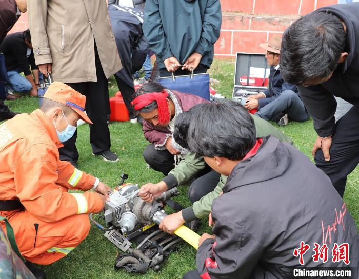 圖為森林消防員為護(hù)林員講解滅火裝備的使用方法?！〔际猩窒乐ш?duì) 供圖