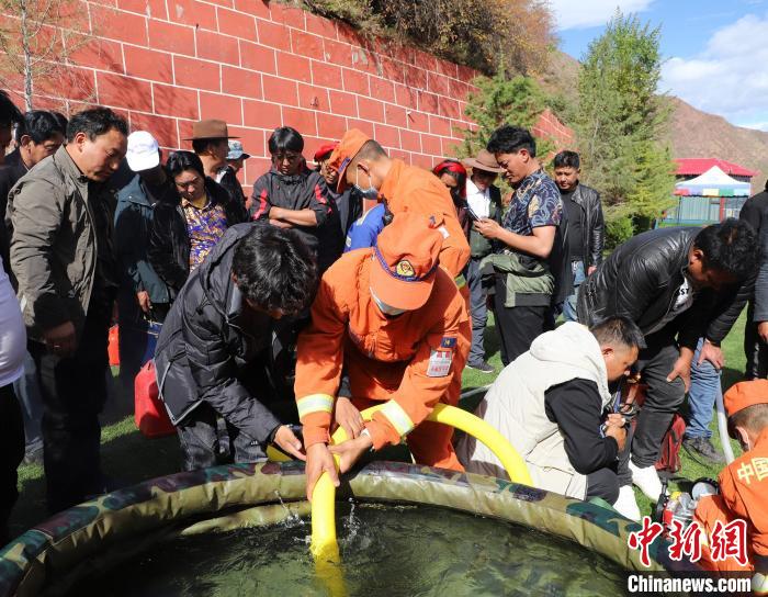 圖為森林消防員為護(hù)林員講解滅火裝備的使用方法?！〔际猩窒乐ш?duì) 供圖