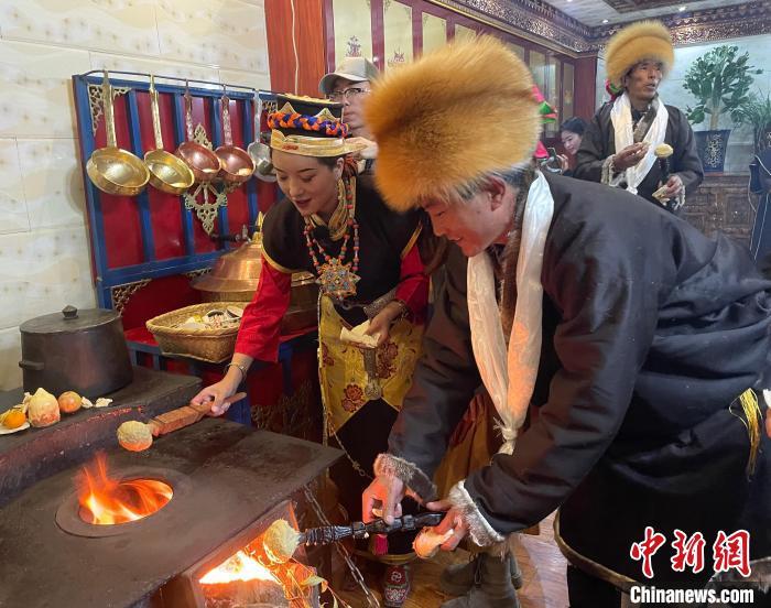 圖為人們在火上烤節(jié)日美食“結(jié)達”?！∪轿木?攝