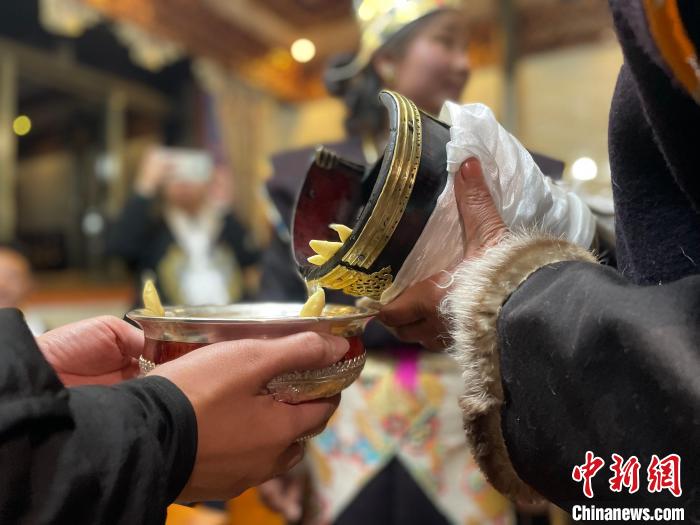 圖為主人在碗中斟滿青稞酒?！∪轿木?攝