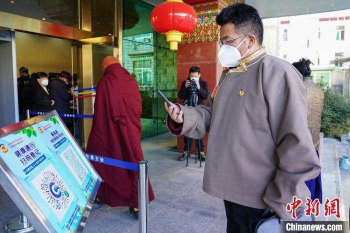 圖為政協(xié)委員掃場所碼進(jìn)入會場?！〗w波 攝