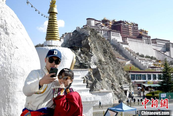 4月17日，游客身著藏式元素服裝在拉薩布達(dá)拉宮觀景臺拍照留念?！±盍?攝