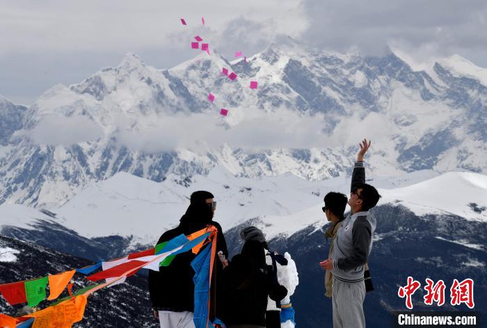 圖為5月14日，游客在西藏林芝色季拉山觀景臺拋灑“隆達(dá)”(風(fēng)馬旗，藏族民眾的一種祈福方式)。　李林 攝