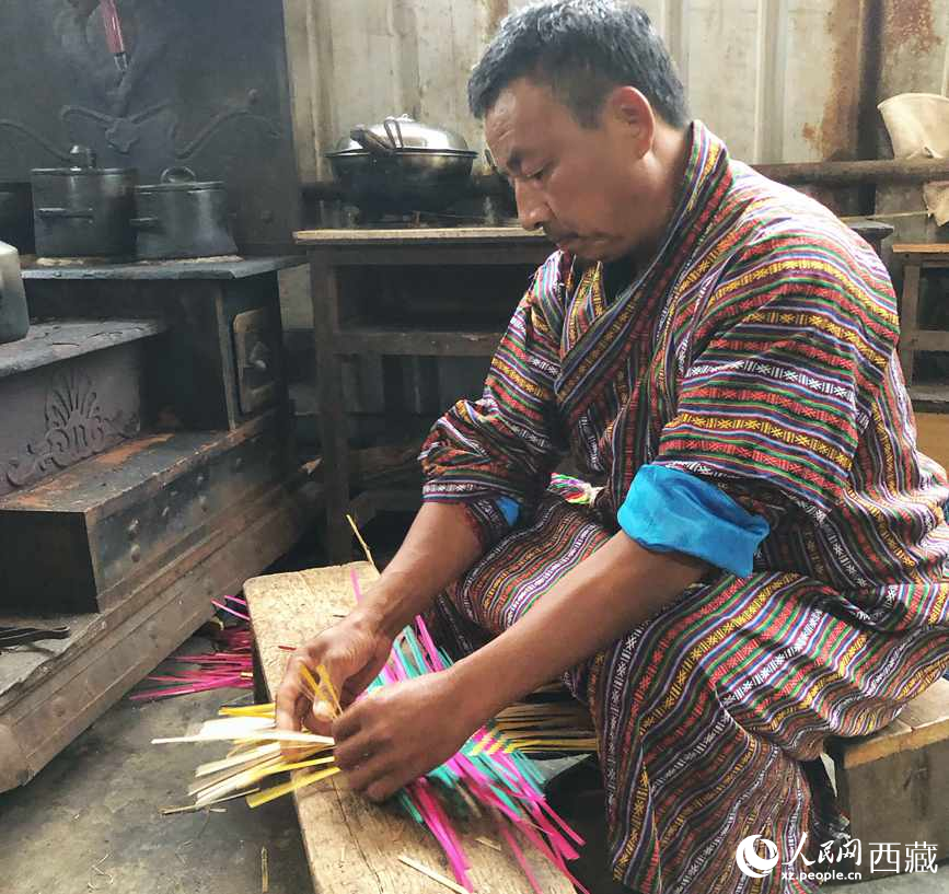 門(mén)巴族漢子愛(ài)明正在編織藤竹品。